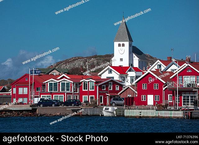 Red houses with a church in the village of SkÃ¤rhamn on the archipelago island of TjÃ¶rn on the west coast of Sweden, blue sky with sun