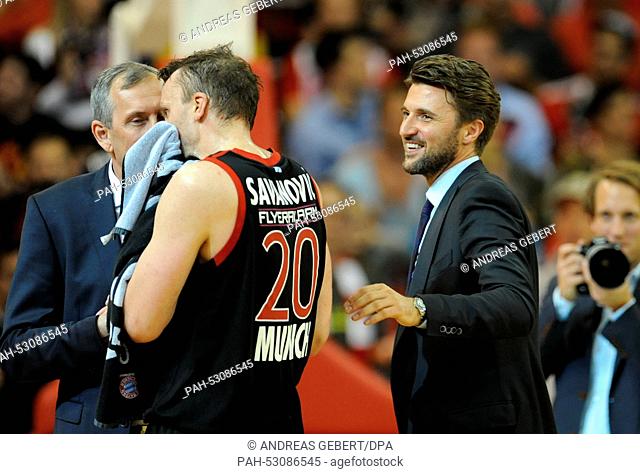 Munich's director of sports Marko Pesic (r) smiles as his father, Munich's coach Svetislav Pesic (l) talks to his player Dusko Savanovic during the basketball...