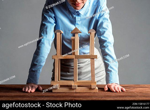 Business woman building construction on table from wooden blocks. Architecture engineering and construction. Company strategy planning