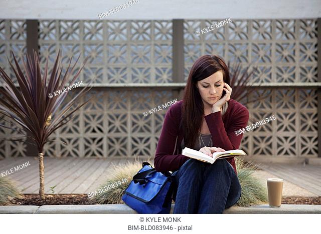 Caucasian woman reading book outdoors