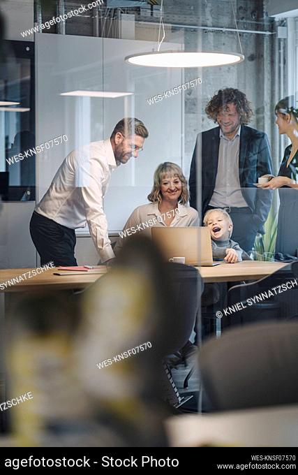 Business team with boy looking at laptop in office