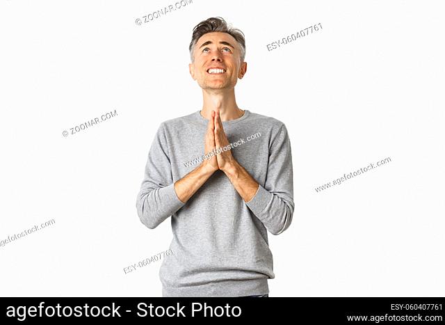 Image of nervous middle-aged man begging God, looking up and pleading for something, supplicating over white background