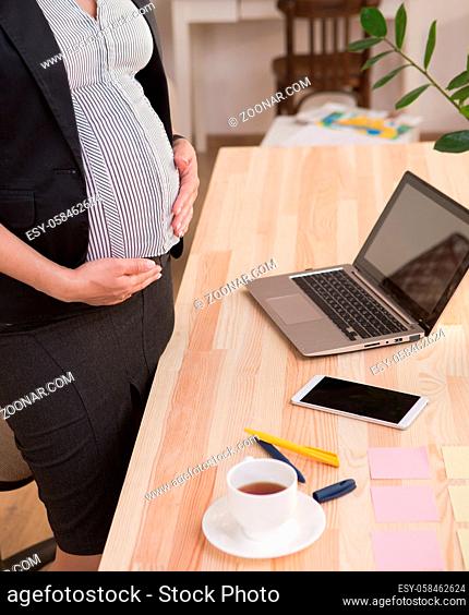Closeup profile of laptop computer of pregnant business woman. Lady working as freelancer at home alone. Business, freelance, pregnancy concepts