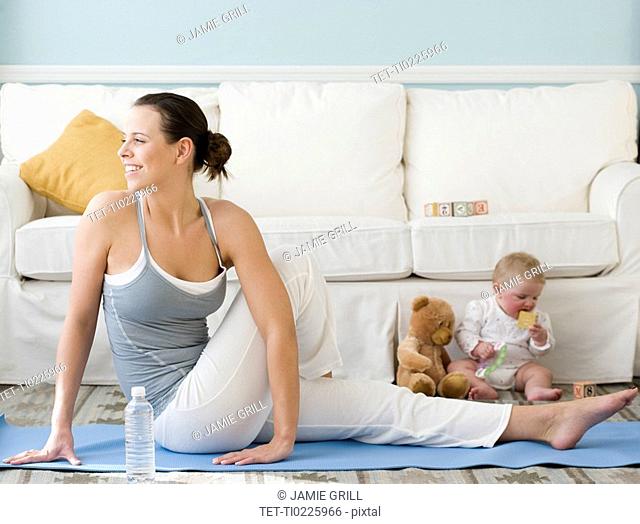 Mother practicing yoga next to baby on floor