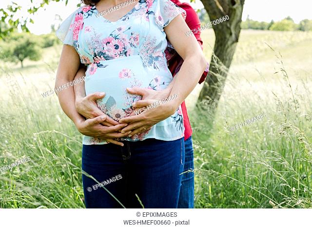 Pregnant woman and man holding baby belly