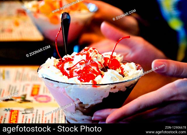 Tasty sweet cherry ice-cream with open hands and a spoon