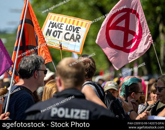 10 September 2023, Bavaria, Munich: A sign reading ""Make love not car"" is seen next to flags of Extinction Rebellion at the final demonstration against the...