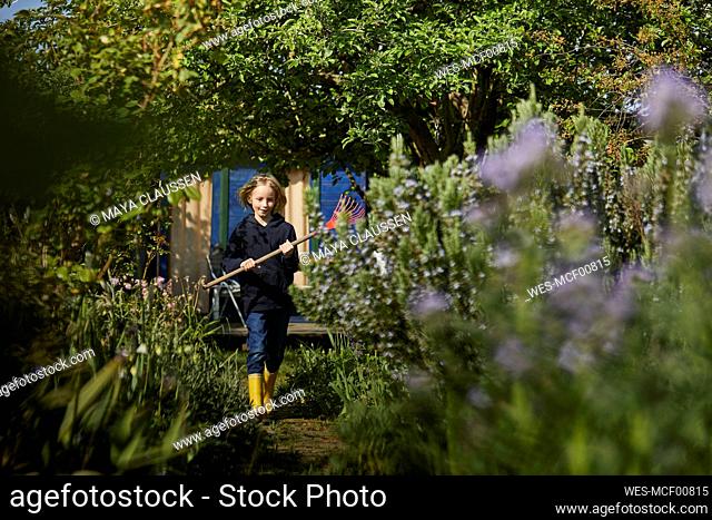 Girl in allotment garden holding a rake