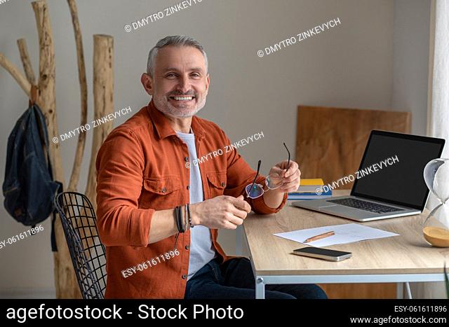 Feeling good. A gray-haired man in orange shirt looking happy