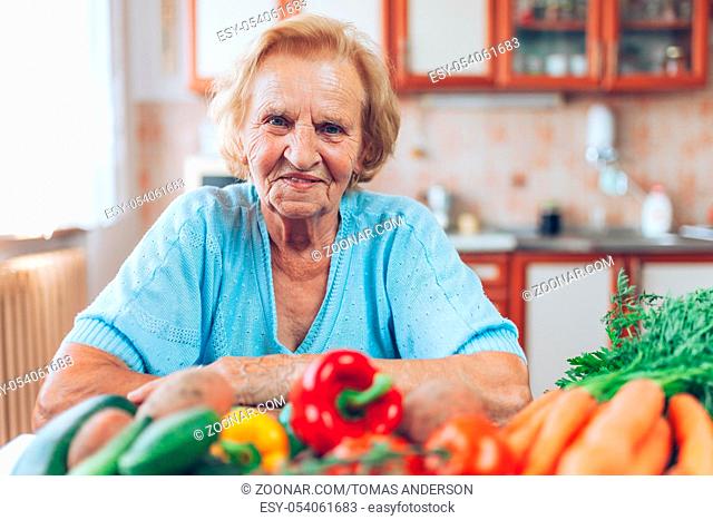 Happy senior woman at home with fresh crop from her garden