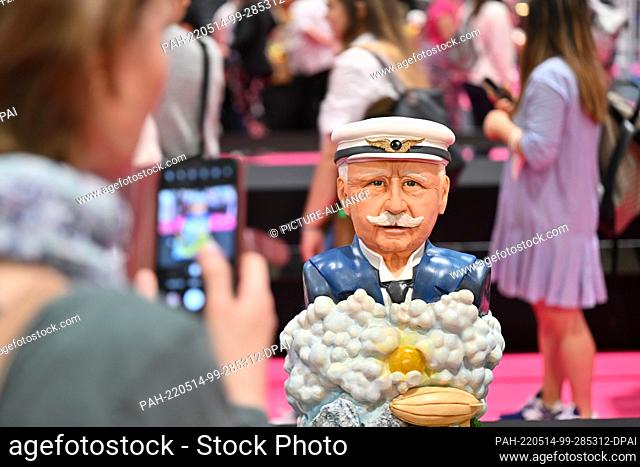 14 May 2022, Baden-Wuerttemberg, Friedrichshafen: A visitor uses her cell phone to take a picture of a cake featuring Ferdinand Graf von Zeppelin