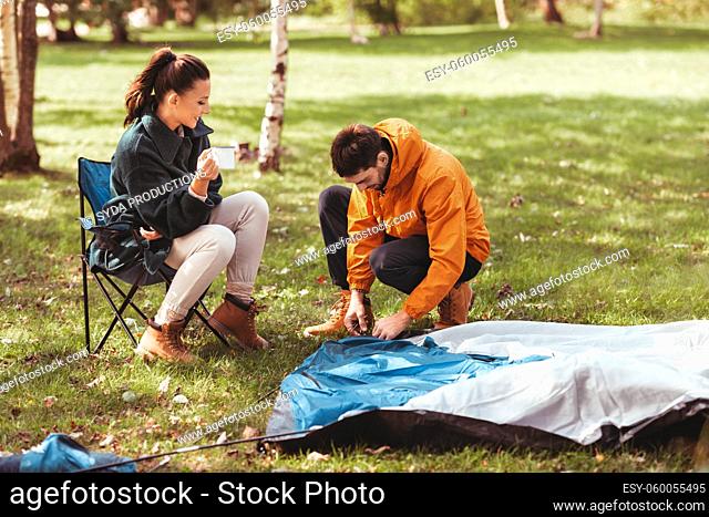 happy couple setting up tent outdoors