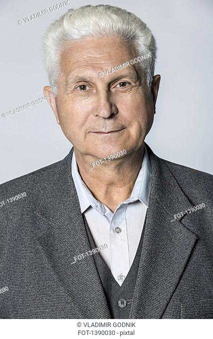Portrait of confident senior man over gray background