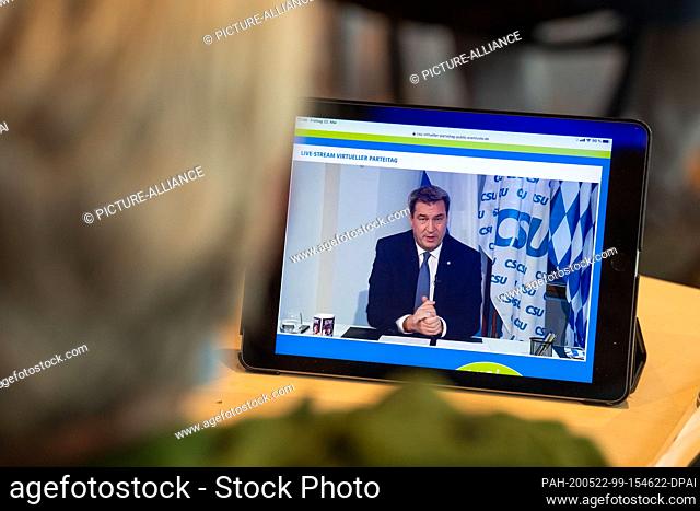 22 May 2020, Bavaria, Munich: A journalist watches the live stream from the CSU party conference, where Markus Söder (CSU)