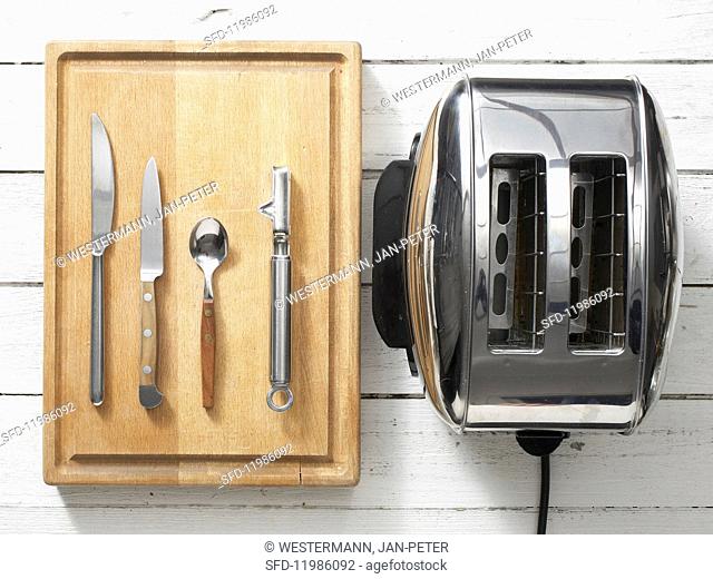 Assorted kitchen utensils: cutlery, a vegetable peeler and a toaster