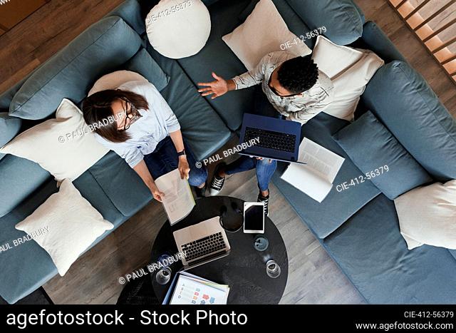 Businesswomen with laptops and paperwork meeting on office sofa