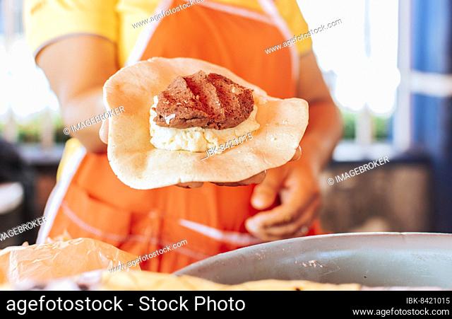 Preparation of the dough for traditional Nicaraguan pupusas, Elaboration of traditional mixed pupusas, Hands of a vendor showing traditional raw pupusa