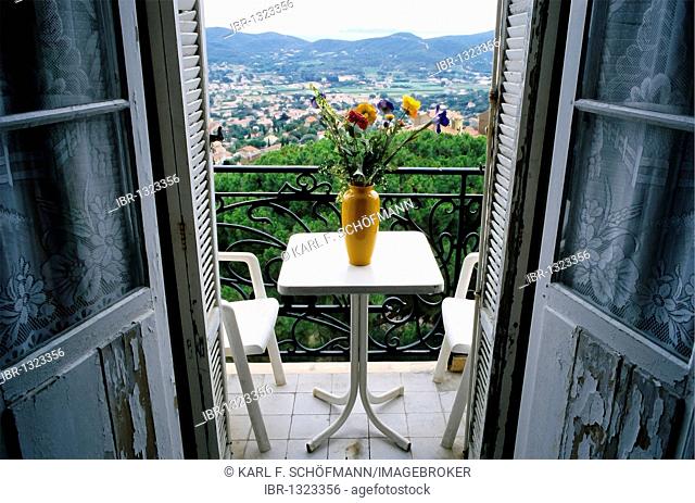 View from a room to a balcony with a table and a vase of flowers, damaged doors, hotel in need of renovation, Bormes-les-Mimosas, Provence-Alpes-Cote d'Azur