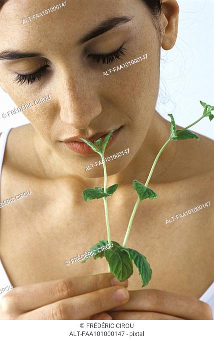 Young woman smelling fresh mint, eyes closed