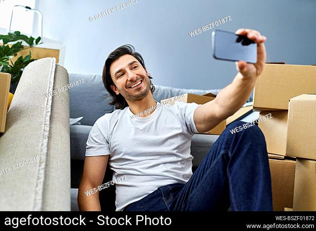 Man taking selfie through smart phone while sitting at home