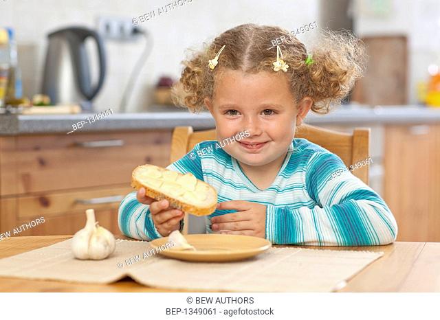 Adorable girl eating sadwich with garlic