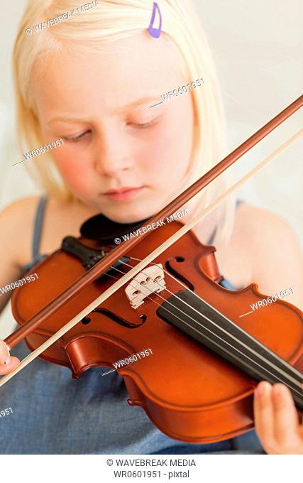 A girl plays the violin sweetly as she closes her eyes