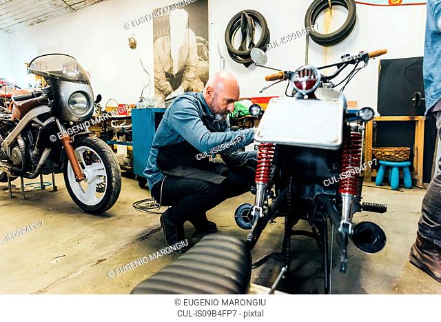 Mature man, working on motorcycle in garage