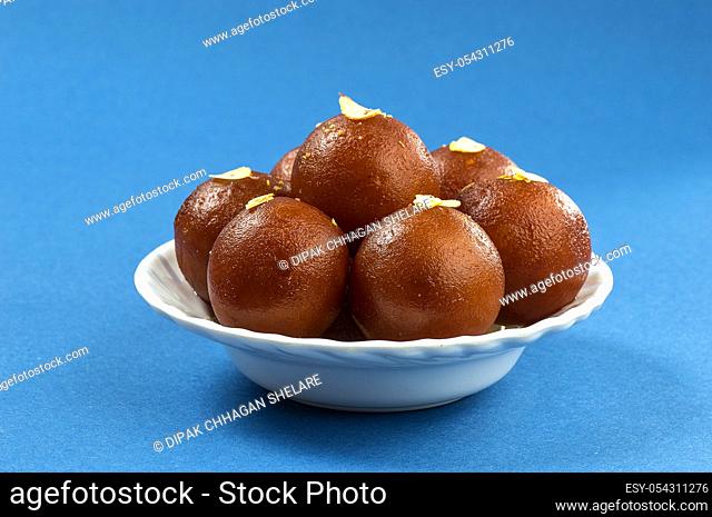 Gulab Jamun, Indian dessert with dry friut in white bowl with napkin