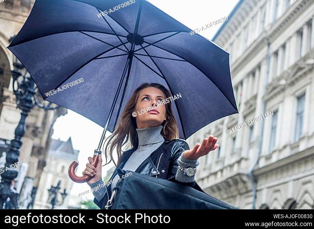 Businesswoman looking away under umbrella during rainy season in city