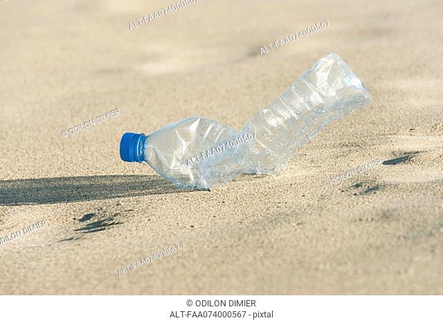Empty plastic bottle on beach, close-up