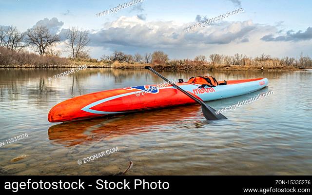 Fort Collins, CO, USA - March 13, 2020: A long racing flatwater stand up paddleboard (Mistral Stealth) on a calm lake after paddling workout in early spring -...
