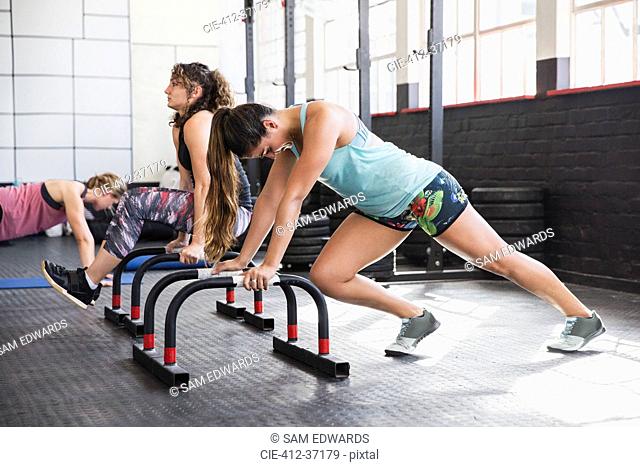 Young woman stretching legs at equipment in gym