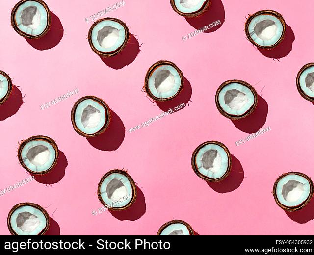 Creative layout of coconuts half on pink background. Tropical pattern, top view or flat lay. Hard light pop art minimal summer background