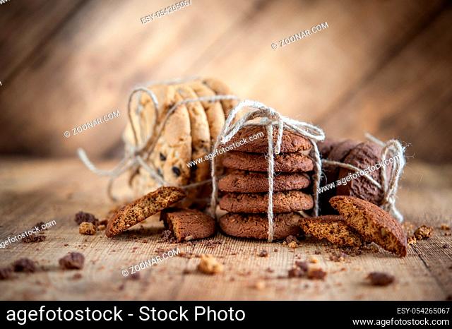 Homemade corded wholegrain cookies with oatmeal, linen and sesame seeds and traditional american cookies with chocolate chips on dark rustic wooden table