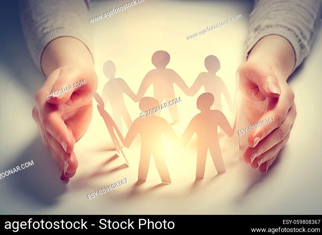 Paper people surrounded by hands in gesture of protection. Concept of insurance, social protection and support