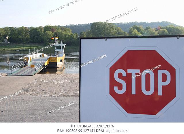 08 May 2019, Saxony, Dresden: A stop sign stands in front of a car ferry on the banks of the Elbe in Dresden's Kleinzschachwitz district