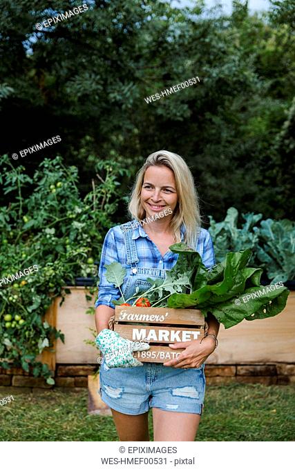 Blond woman with wooden box and organic vegetables
