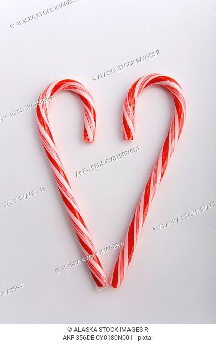 Closeup of two Christmas candy canes in the shape of a heart blurred at top on white background studio portrait