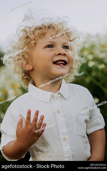 Happy baby boy standing at flower field