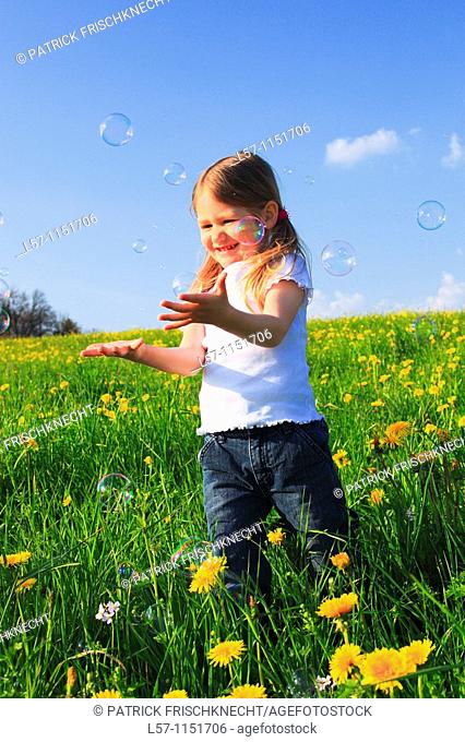 girl playing with bubbles in field of Dandelions, Zuercher Oberland, Zuerich, Switzerland
