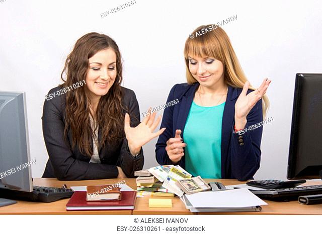 for office table two women collaborators happily looking at a lot of money on the table