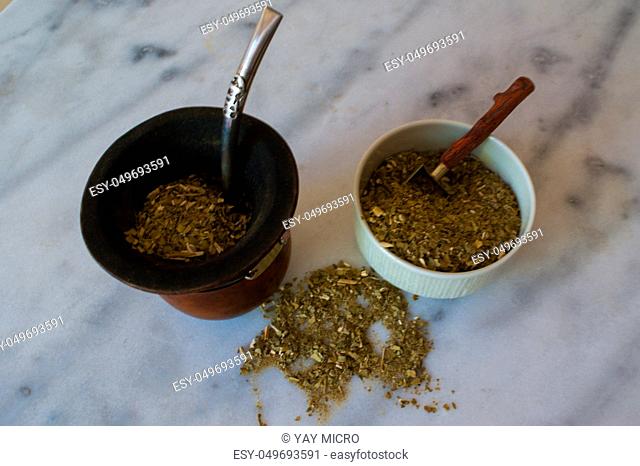 A yerba mate infusion with a withe marble background. A wooden gourd and the metal straw