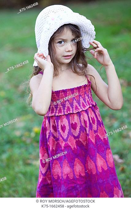 Little girl holding her hat on her head