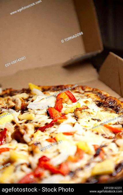Barbeque chicken, red bell pepper, onion, pineapple pizza in its carryout box