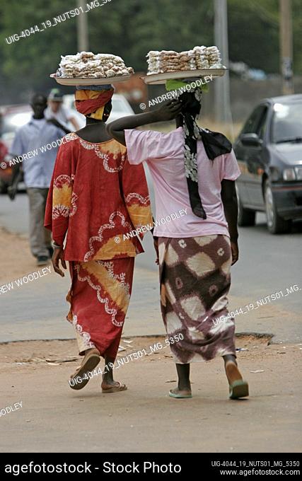 Two women carrying platters of nuts on heads Bakau The Gambia
