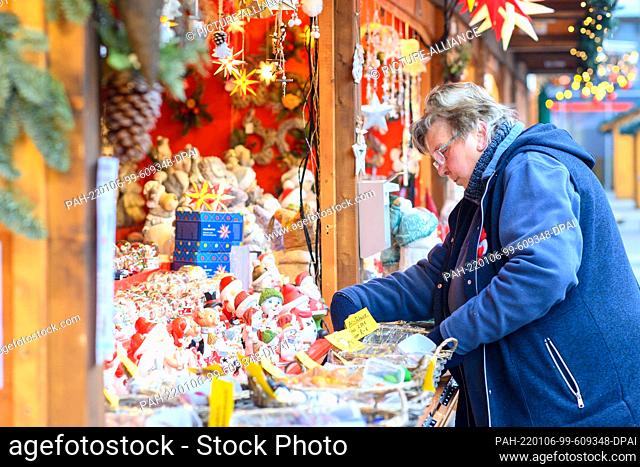 08 December 2021, Saxony-Anhalt, Magdeburg: A Christmas market vendor sorts through her wares as she opens her stall. Photo: Klaus-Dietmar...