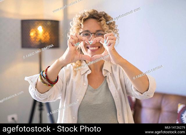 young woman doing heart shape gesture with hands. beautiful woman flirting and smiling on camera. attractive cheerful woman making a heart shape symbol using...
