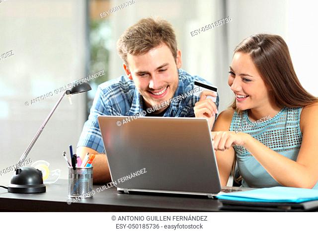Happy couple comparing online products buying on line with a laptop and credit card