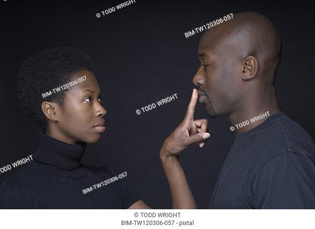 African woman putting finger on boyfriendÆs lips