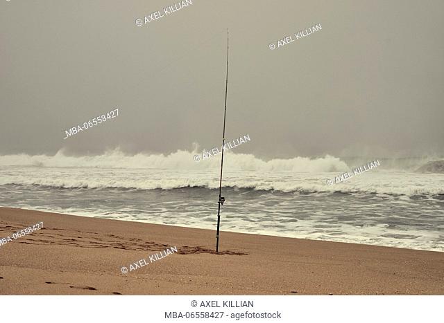 Fishing rod in the ground on the beach, sea, waves, surf, foam